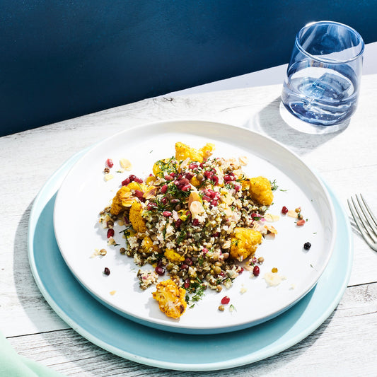spiced cauliflower salad with coloured rice, pomegranate on a white plate