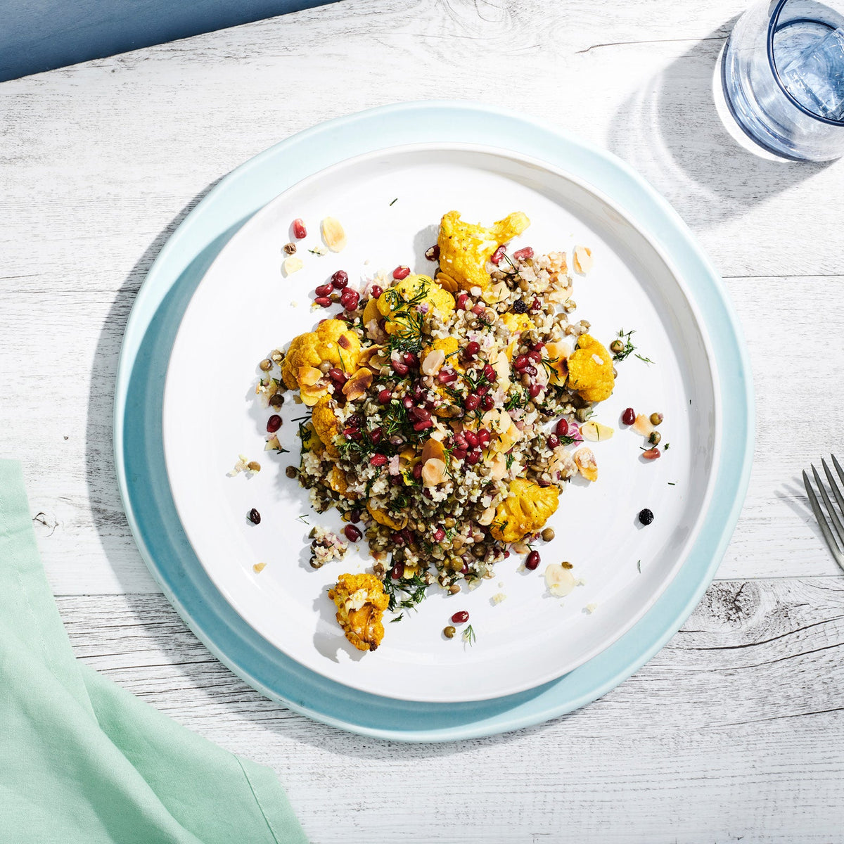 spiced cauliflower salad with coloured rice, pomegranate on a white plate
