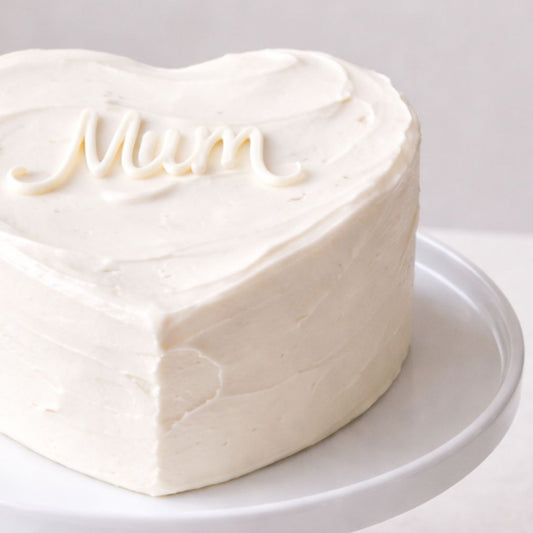 Heart-shaped cake with 'Mum' written on top on a white plate
