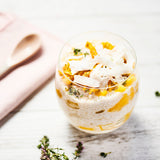 A glass filled with coconut chia pudding topped with seasonal fruit and coconut