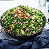 Large bowl of green salad with noodles and protein