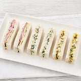 Platter of mixed finger sandwiches on a white surface