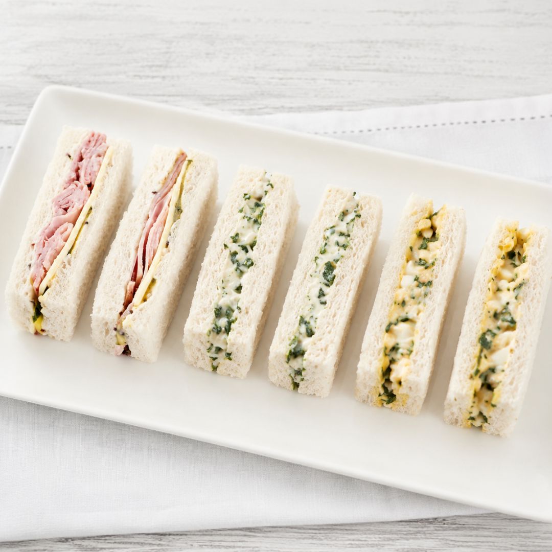 Platter of mixed finger sandwiches on a white surface