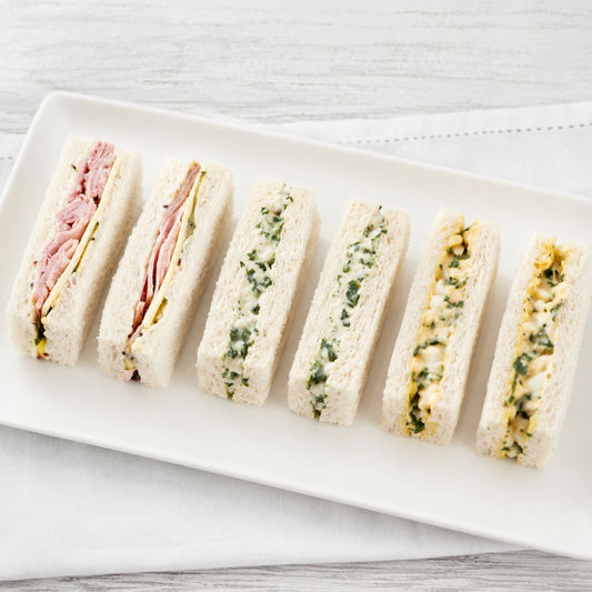 Platter of mixed finger sandwiches on a white surface