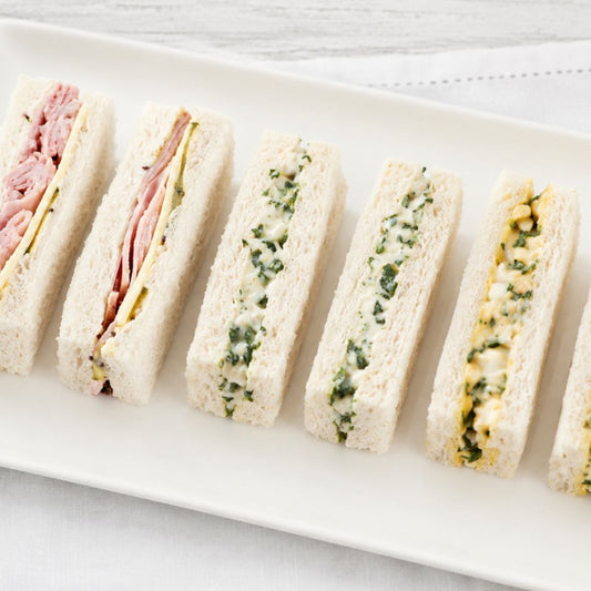 Plated assortment of mixed finger sandwiches on a white plate