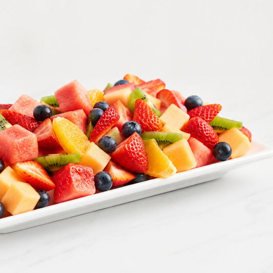 Assorted fruit salad on a white plate with a white background