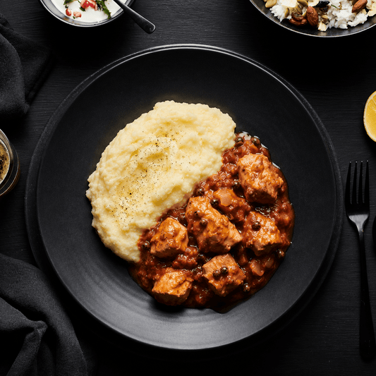Black plate with mashed potatoes and syrian chicken dish