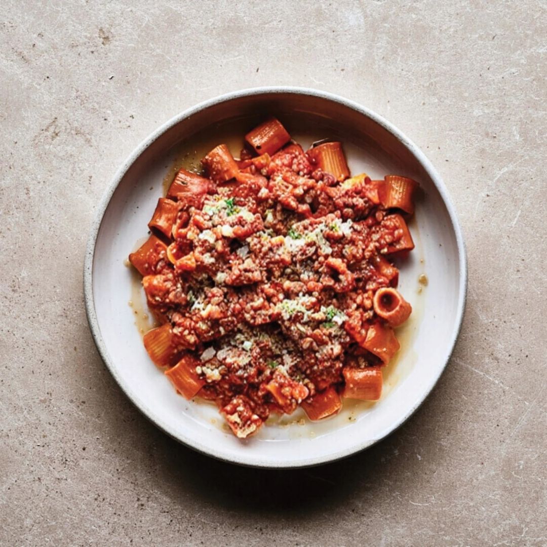 Tubetti pasta with red rigati bolognaise sauce on a grey plate