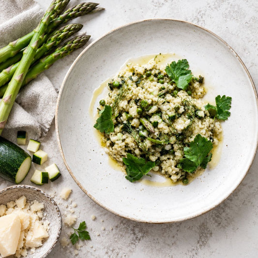 A plate of zucchini, asparagus risotto with a garnish of parsley on top. 