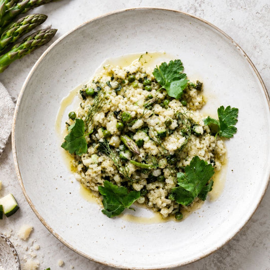 A plate of zucchini, asparagus risotto with smoked scamorza and a garnish of parsley on top